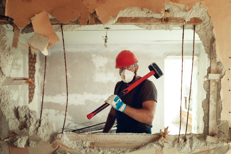 22 02 16 a person holding a sledgehammer in front of a big hole in a wall gettyimages 1279338623