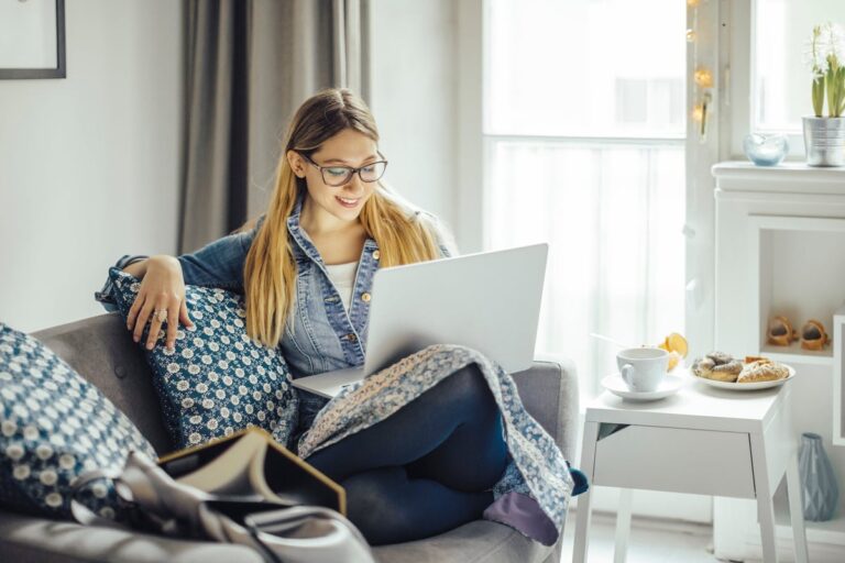 Young woman using laptop on the couch. KUYgdGZ