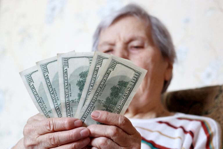 elderly woman retirement social security holding 5 one hundred dollar bills