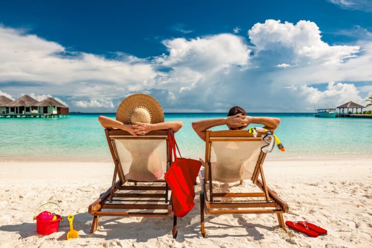 gettyman and woman relaxing in lounge chairs on a beach in the maldives