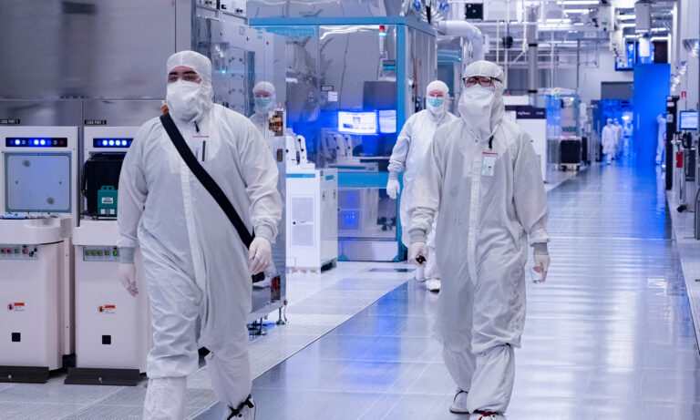 inside intel factory two people in lab gear walking intel