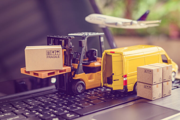 miniature of yellow van boxes and pallet truck on top of black laptop