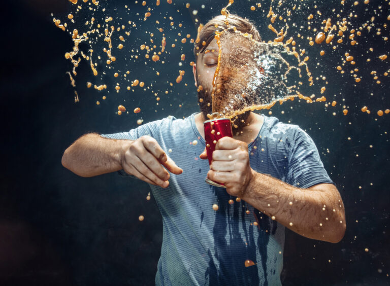 person holding an exploding soft drink can