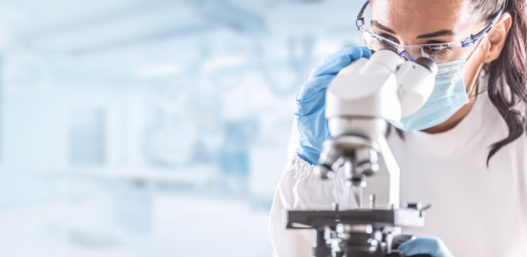 person in a lab looking through a microscope