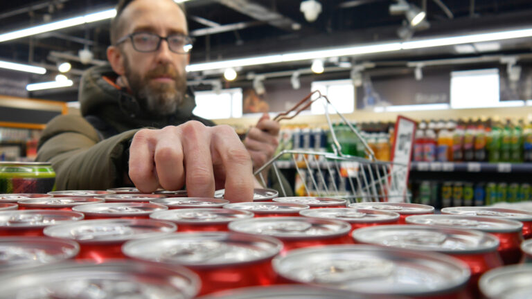 person taking a red can in a supermarket