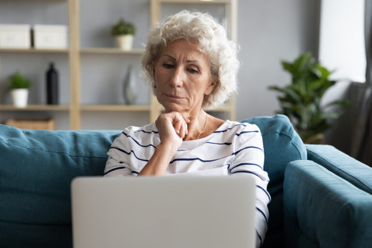 person with hand on chin looking at laptop