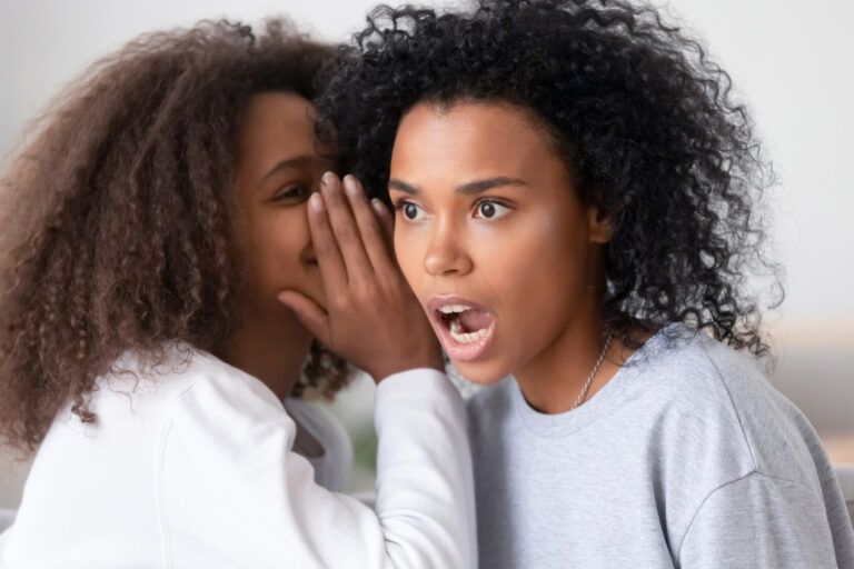 22 07 19 a person whispering into the ear of another person that is surprised gettyimages 1232128517