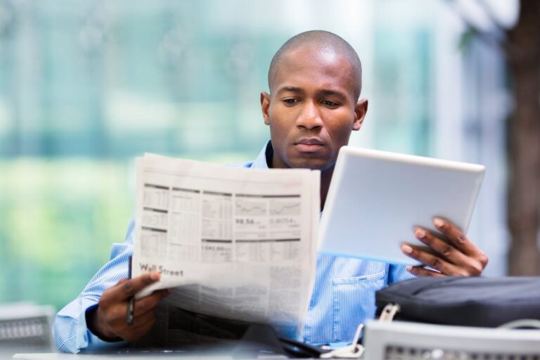 Man reading newspaper and looking at a tablet kXXl02u