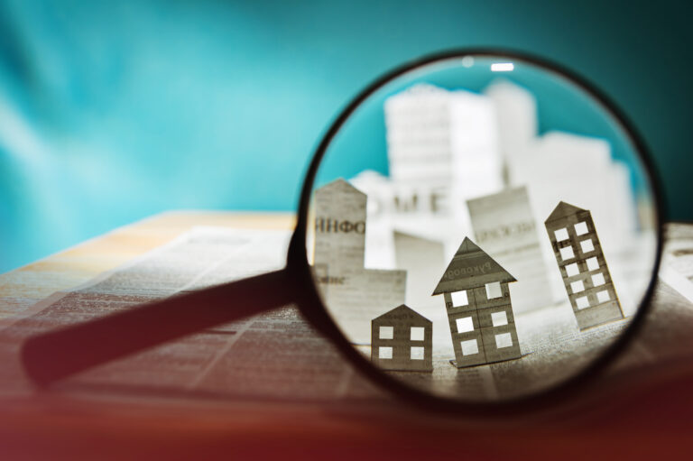 a magnifying glass used to focus on cardboard cutouts of real estate properties