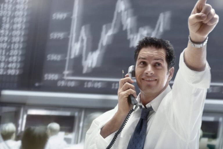 a person on the phone pointing to movement on a stock chart