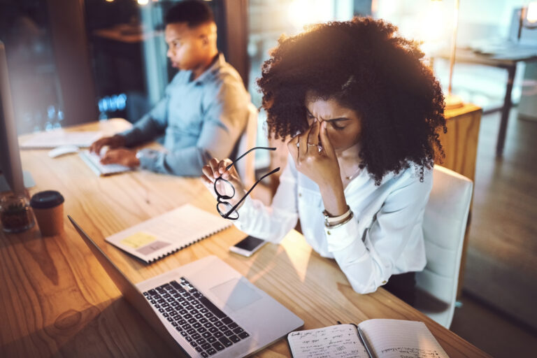 person at desk in front of laptop with hands on face