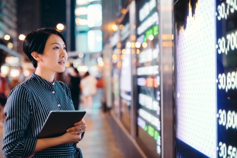 a person looking at the tickers for a stock market exchange