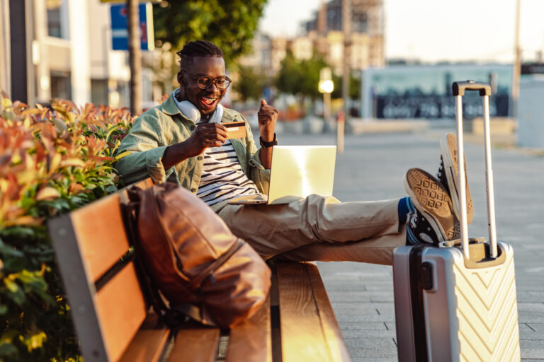 a person sitting on a bench with a laptop computer and a credit card