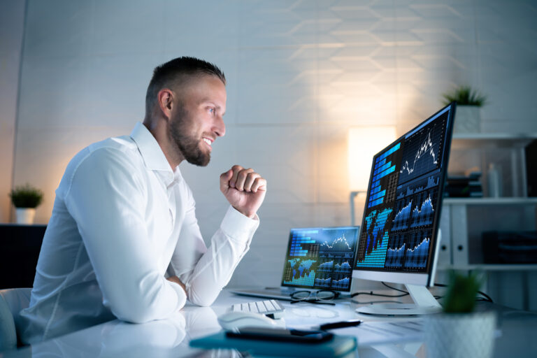 an excited investor looks at financial charts on computer