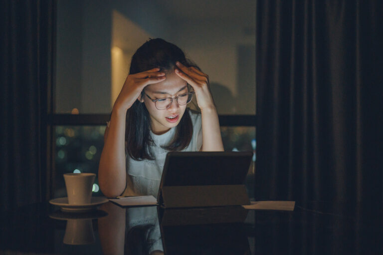 concerned young person with head in hands gazing at a screen