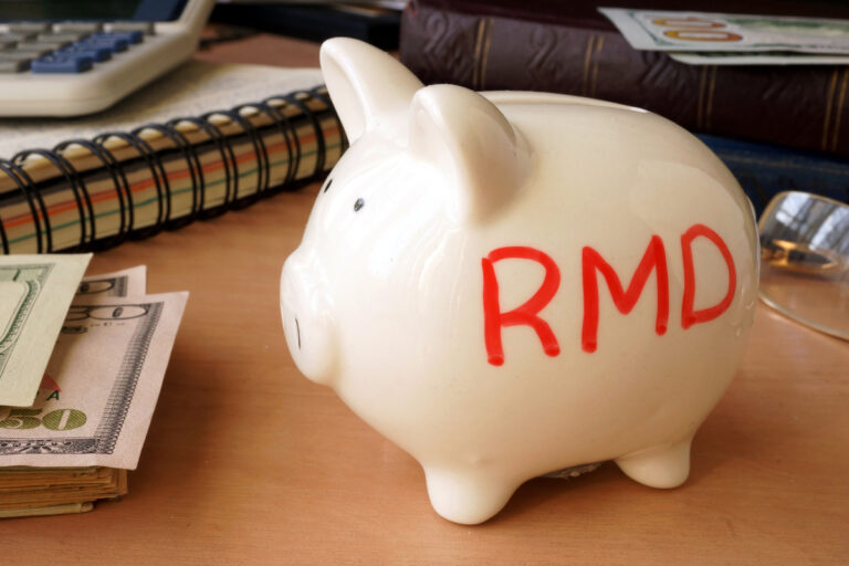 getty images piggy bank with rmd written on its side next to stack of paper money retirement savings 401k ira cash 1200x800 5b2df79