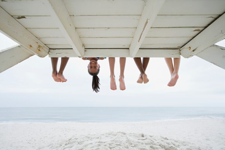 peoples legs sticking out from under a boardwalk with one face