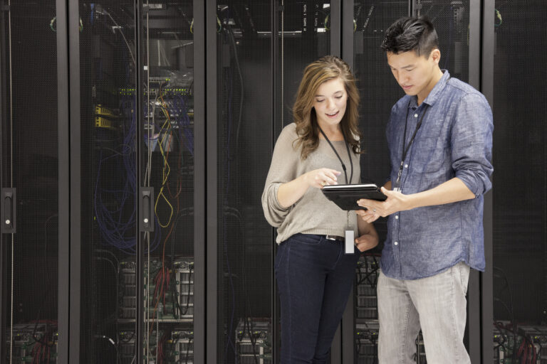 people viewing a mobile device in front of stacks of supercomputers