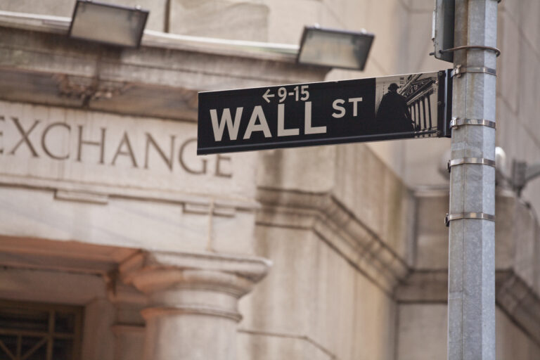 a photo of the wall street street sign with the stock exchange in the background