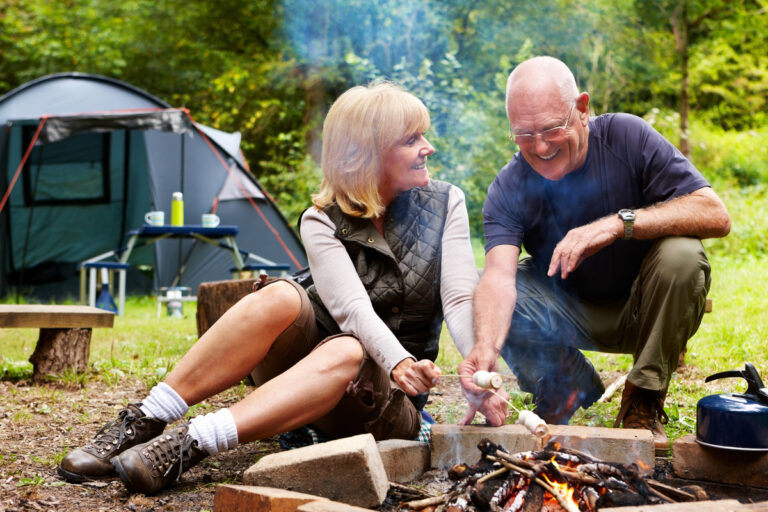 smiling couple roasting marshmallows at campsite